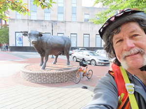 Ted and his bike in front of Bull statue in Durham.