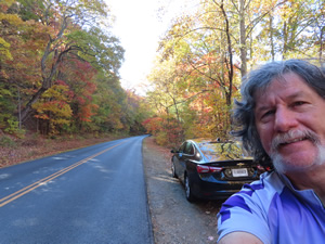 Ted with his rental with the fall colored tress on the road descending from Mount Mitchell.