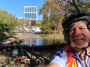 Ted with his bike at Falls Park with liberty bridge in the background.