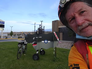Ted with his bike in front of town theme plywood bull in Rock Springs, Wyoming.