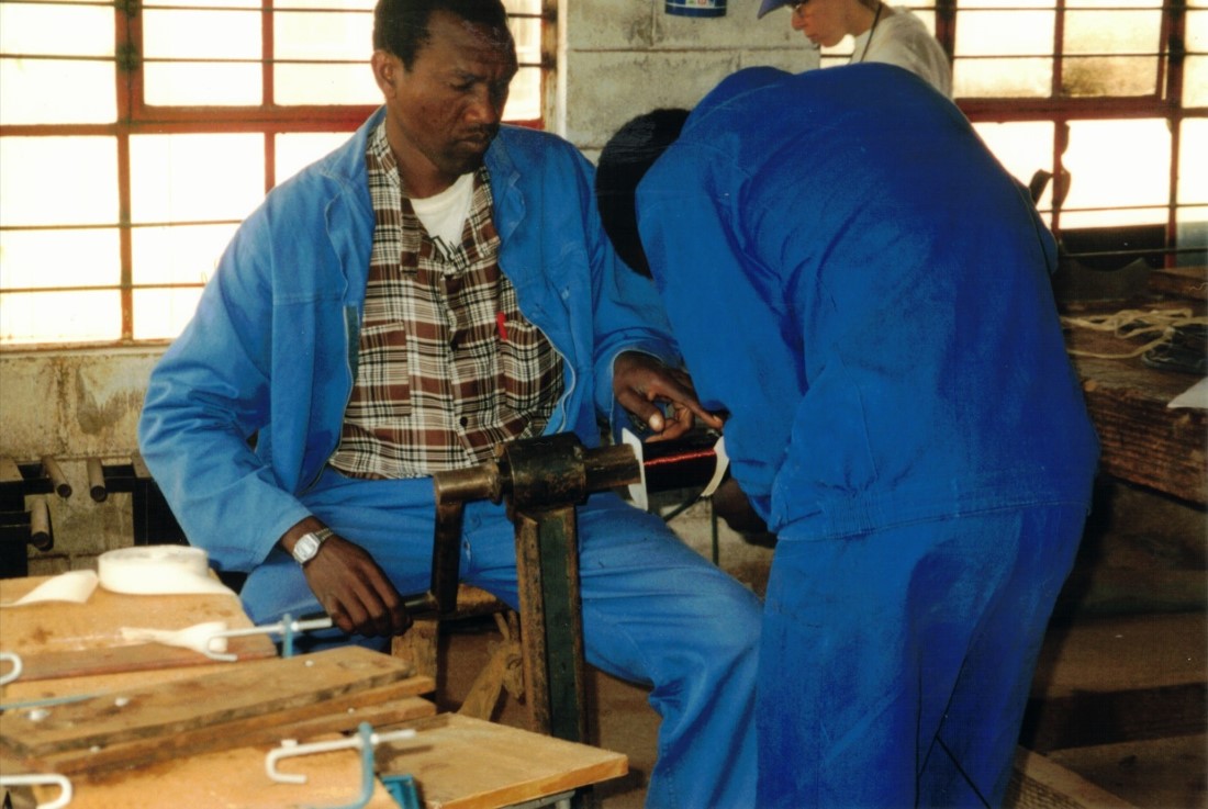 A couple of men winding a coil in order to build a welder at the Hlekweni training center.