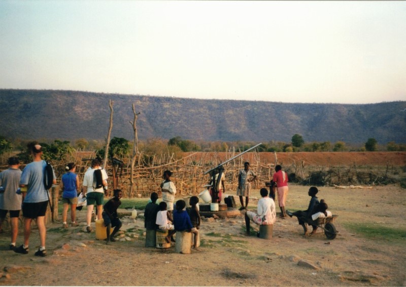 Getting water by the school at Sianzyundu.  They often had to stop pumping and wait for the water level to rise.  John at right and Heather is to the left.