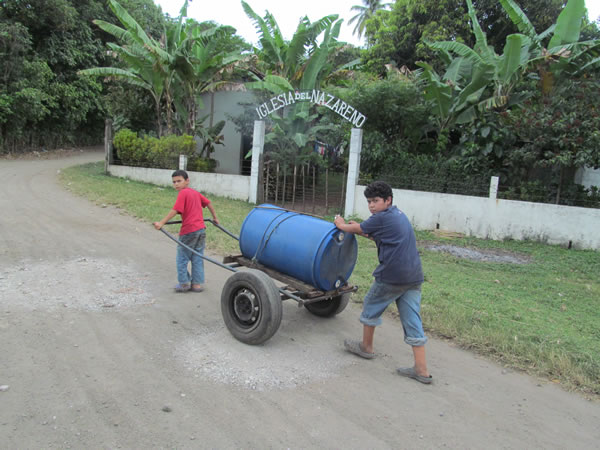 Kids pushing drum of liquid in Nicaragua