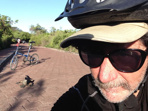 Ted with Iguana and bike behind him at the Charles Darwin research station in Puerto Ayora, Ecuador, Galapagos Islands.