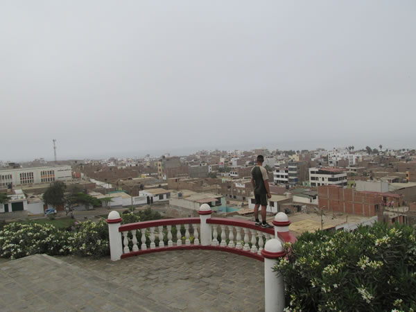 A man standing on the rails in front of a church on the hill at the town of Huanchaco, Peru.