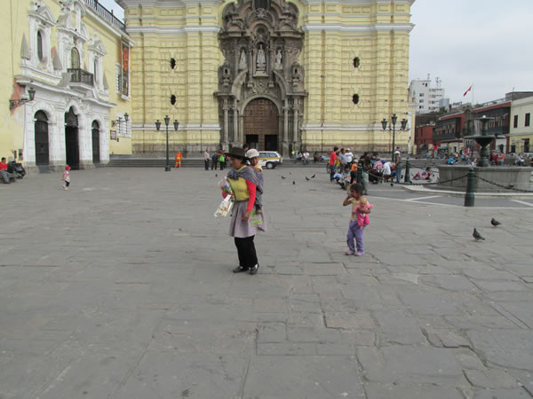 A lady carrying her child in front of San Francisco church in historic center of Lima, Peru. This church contains thousands of skulls and bones in the basement full of bones, dating from the 1600 to 1808.