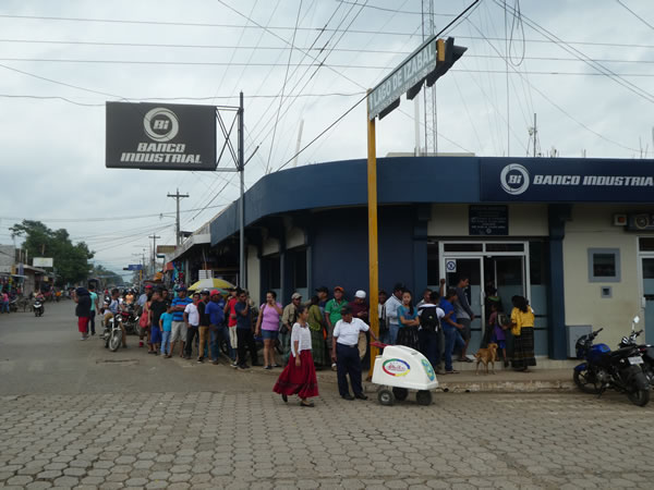 People waiting to go into the bank at El Estor, Guatemala. (lines like this are common at Latin American banks)