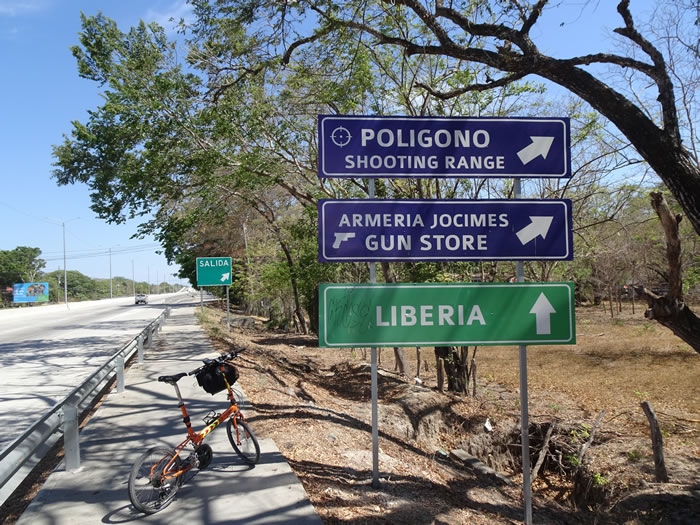 Ted’s bike next to gun shop sign near Liberia, Costa Rica.