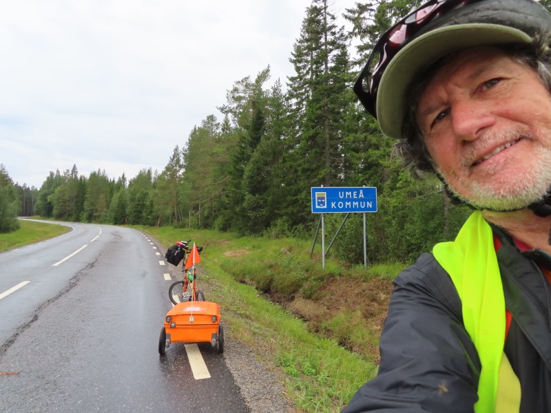 Ted and his bike near sign next to road between Bygdsiljum, Sweden and Sanabadets, Sweden.