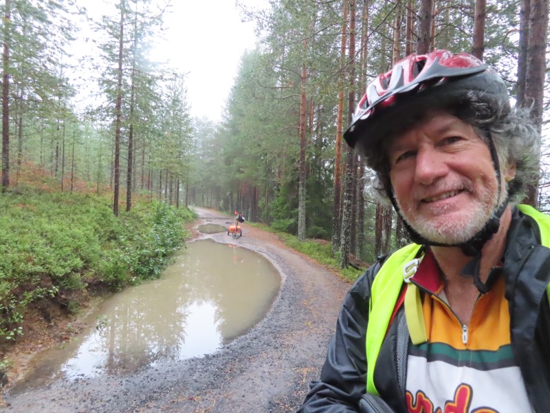 Ted with his bike on road leaving Sanabadets campground in Sweden. It rained hard all night at campground.