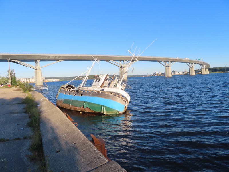 Sinking boat in water by E4 bridge on Baltic Sea inlet in Sundsvall, Sweden.