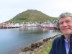 Ted with the town of Honningsvåg, Norway and hill behind him that he hiked half way up.