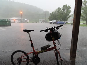 Ted’s bike seen from shelter while downpour in Monongah, West Virginia. – His rental car is the blue car in the background.