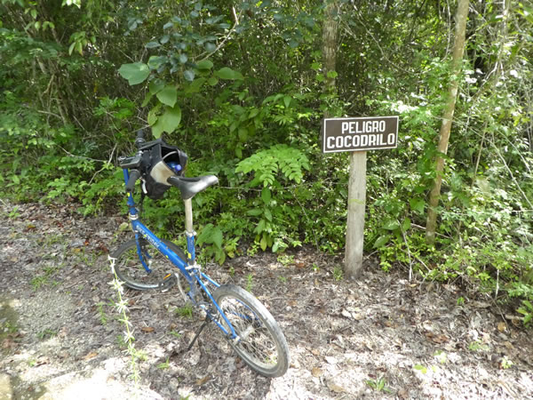 Ted’s bike in front of a sign warning about Crocodiles in Tikal National Park, Guatemala.